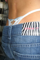 Blue shiny lace thong with cut-out back and pendant, styled under low-rise jeans with a Miss Y patch