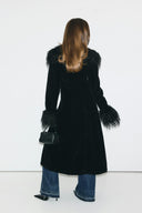 Black faux fur figure-hugging full-length coat with shaggy cuffs and seamed back, back view on model