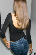 Black padded bodysuit with low scoop back and 3/4 sleeves, back view on model