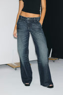 Vintage blue low-waist baggy jeans with front pockets and raw-edge hems, front view on model