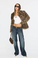 Tiger print faux fur shaped jacket with long sleeves, styled with wide blue jeans, front view on model