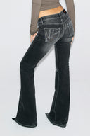 Black low-waist bootcut tall jeans with rhinestone Miss Y logo on the back pockets, back view on model