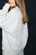 Grey melange oversized crew neck sweater with dropped shoulders and ribbed hem, side view on model