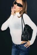 Off-white sheer tight-fit turtleneck body with long sleeves, styled with blue jeans and a black bag, front view on model