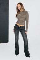 Grey tight-fit drapey top with ruched front and long sleeves, full-length front view on model with black jeans