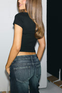 Black tight-fit baby tee with short sleeves and cropped hem, back view on model