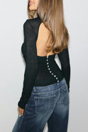 Black sheer top with open back and buttons down the back, back view on model