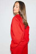 Red baggy crew neck sweater with long raglan sleeves, back view on model
