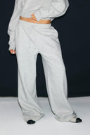 Grey melange loose-fit low-waist sweatpants with drawstring and full-length baggy leg, front view on model, waist down