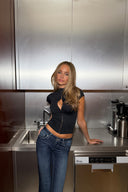 Black tight-fit keyhole top with high collar and short sleeves, styled with blue jeans, in a steel kitchen