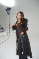 Dark brown faux fur coat with shaggy collar and cuffs, styled with dark jeans in a photo studio