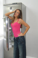 Cerise (pink) figure-hugging bodysuit with deep neckline and thin straps, styled with blue jeans by an open fridge