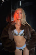 Leopard print satin push-up bra with light blue lace trim, styled with a brown faux fur coat in warm low light