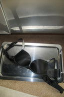 Black super push-up bra with rhinestone straps and smooth padded cups, styled on a metal tray