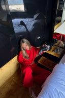 Red loose-fit wide-leg sweatpants, styled with a matching sweatshirt on the floor of a hotel room