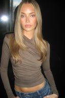Grey tight-fit drapey top with ruched front and long sleeves, styled with blue jeans in a dark interior