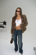 Vintage blue loose-fit low-waist wide-leg baggy jeans, styled with a tiger print faux fur jacket in a studio
