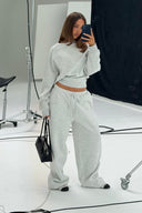 Grey melange loose-fit low-waist sweatpants with drawstring and wide leg, styled with a matching sweatshirt in a photo studio