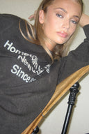 Washed black crew neck top, close-up of the washed white text print on model leaning on a chair