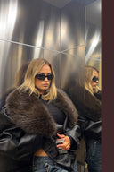 Black faux leather baggy jacket with brown faux fur collar, styled with blue jeans in a mirrored lift