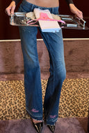 Dark vintage blue loose-fit low-waist wide-leg jeans with pink "Miss Why" hem embroidery, styled with a serving tray