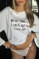 Gardenia (off-white) low-waist mesh thong with rhinestone text and thin straps, front view on model with a white top