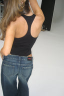 Black ribbed body with racer back, tucked into blue jeans, back view on model in a photo studio