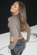 Black low-waist bootcut jeans with rhinestone Miss Y logo, styled with a taupe top in a photo studio