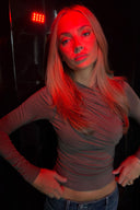 Grey tight-fit drapey top with ruched front and long sleeves, styled under red club lighting