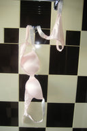 Pink super push-up bra with rhinestone straps, styled with matching thong on a tiled wall