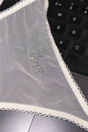 Gardenia (off-white) mesh thong, close-up of the rhinestone Love text and scalloped trim