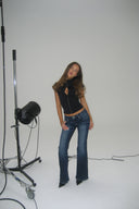 Black tight-fit keyhole top with keyhole cutout, styled with blue flared jeans, full-length in a white photo studio